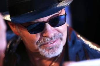 Close-up of a man wearing a black hat and sunglasses, with a gray goatee, looking to the left.