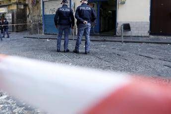 Two police officers in dark jackets stand behind police tape at a storefront crime scene on a city street.”,”Policy: Wildcard”]} }{