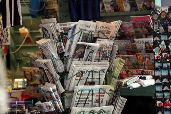 Newspaper stand with folded newspapers arranged in a circular display at a shop window(s).