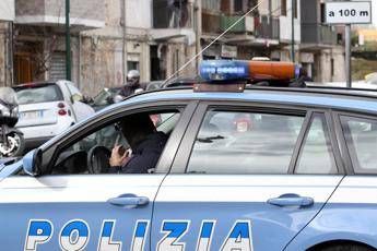 Italian police car with blue lights on a city street, officer visible through the window.